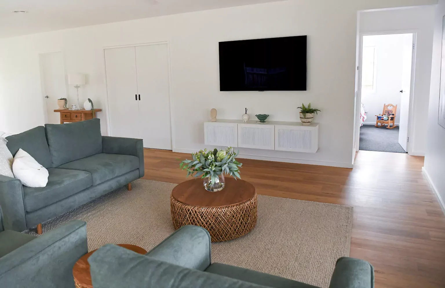 Modern living room with couch, 2 arm chairs, coffee table and TV mounted on wall