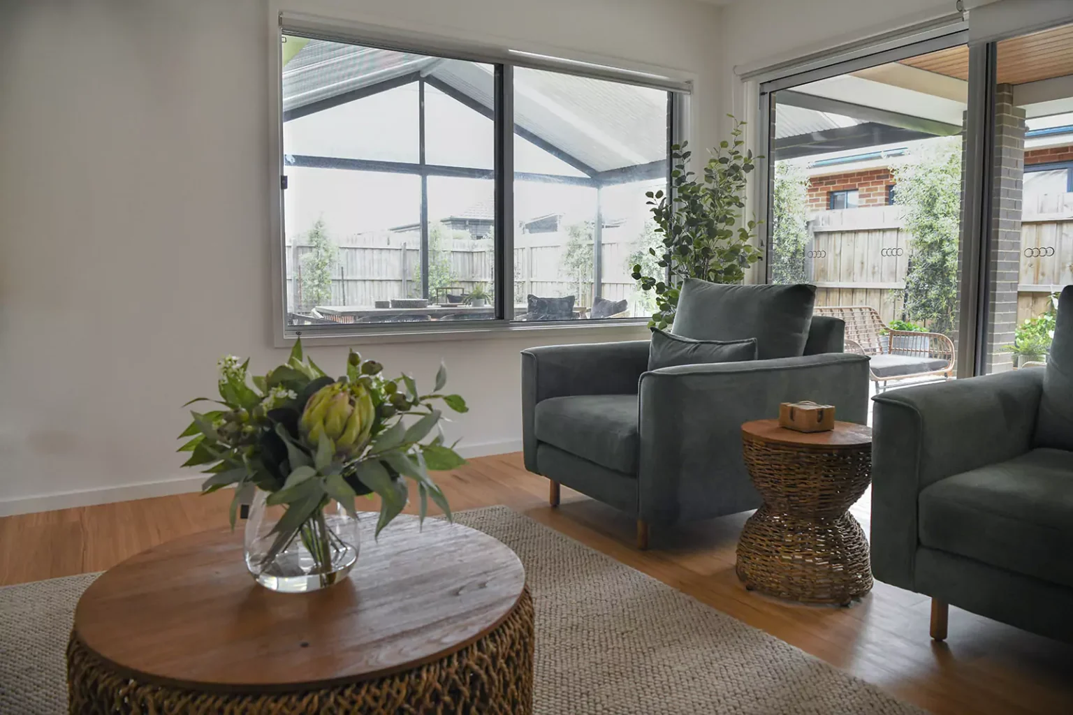 Living room with 2 arm chairs, coffee table and side table with Australian native plants in vase on coffee table