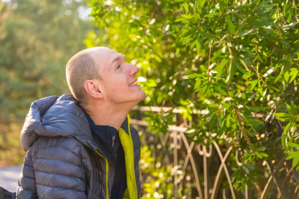 A disabled man smiling looking at the plants